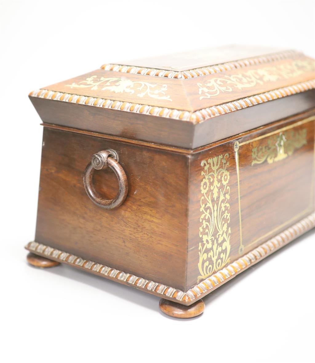 A Regency rosewood and cut brass inlaid sarcophagus shaped tea caddy, (mixing bowl restored), length 33cm